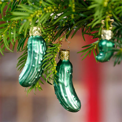 3 grüne Gurken-Weihnachtskugeln an einem Ast in der Nahaufnahme